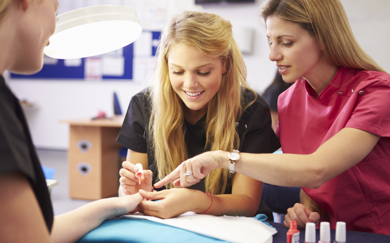 Photo of Cosmetology Student doing nails on a client with instructor helping
